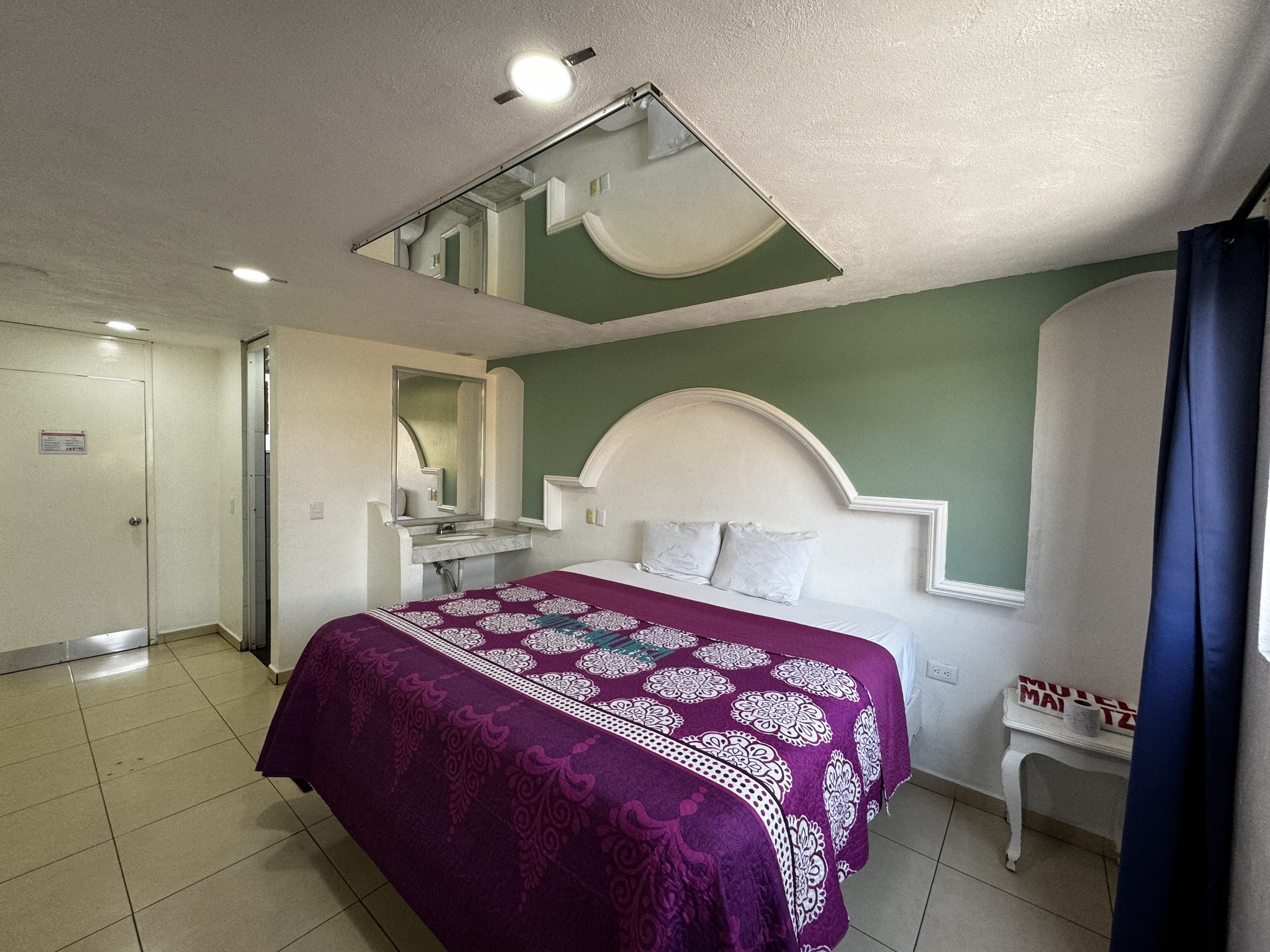Habitación con colcha morada, arco blanco y pared verde claro