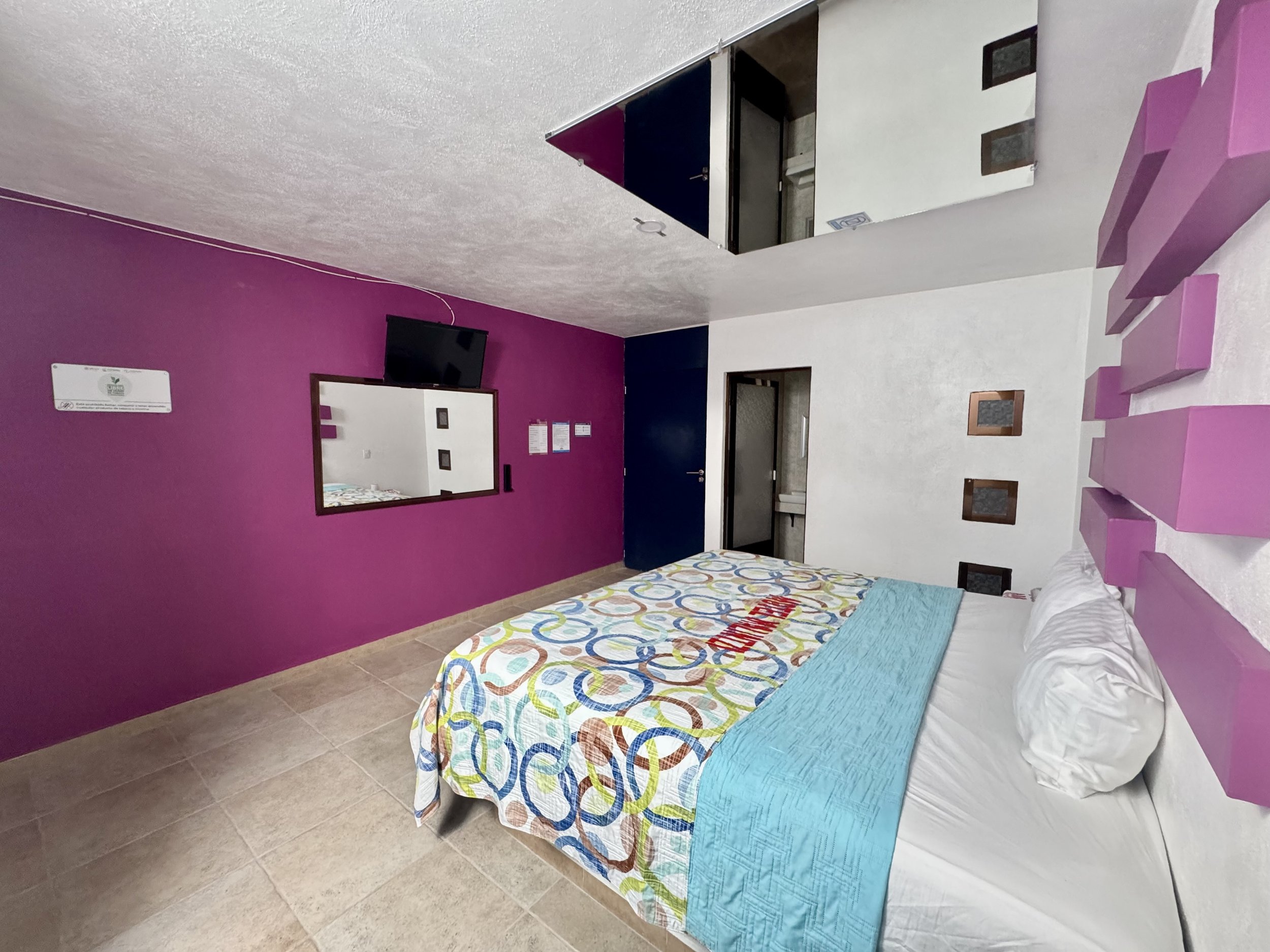 Habitación con pared magenta, televisor y decoración geométrica