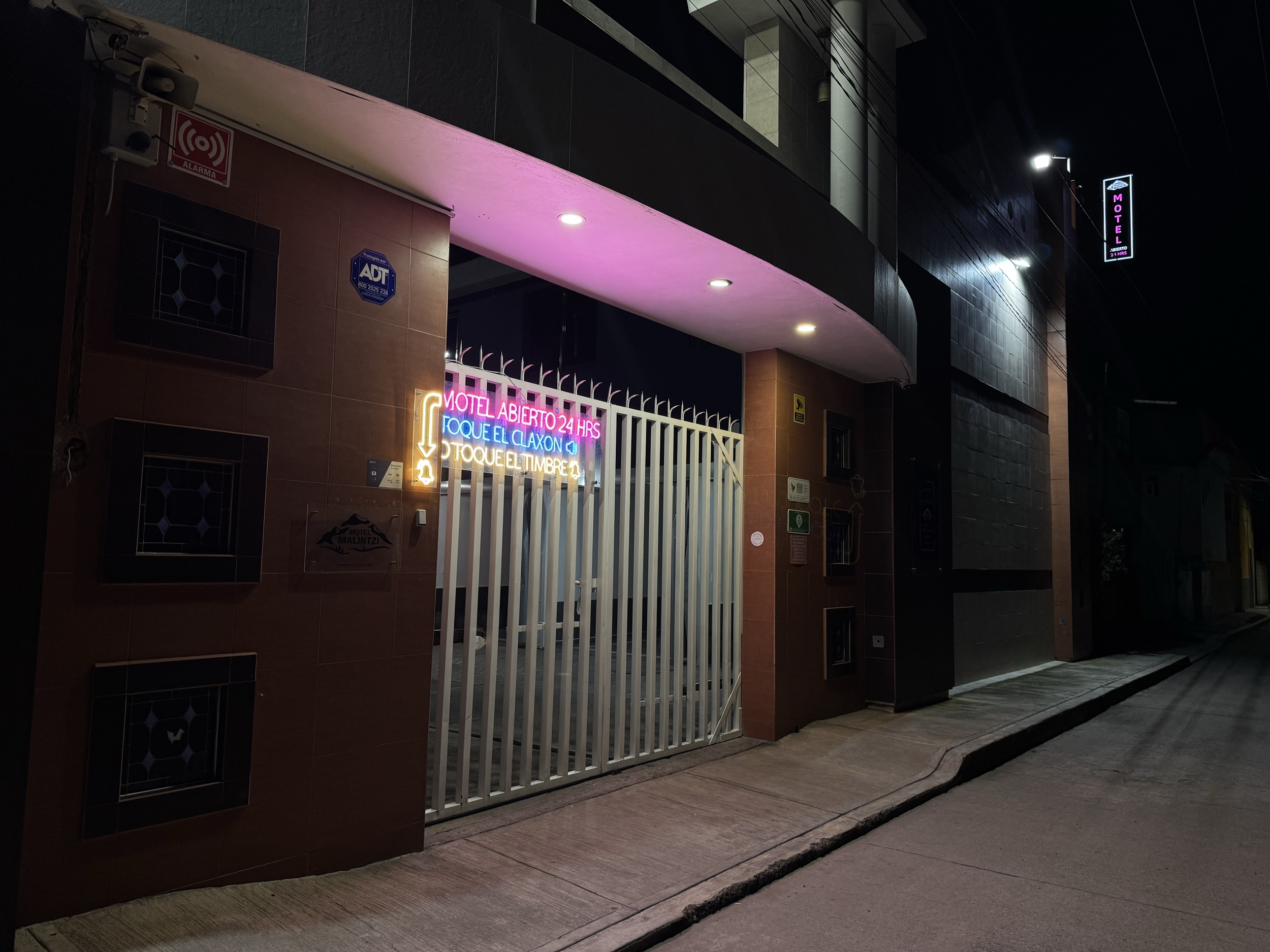 Entrada de Motel Malintzi de noche con letrero de neón: abierto las 24 horas